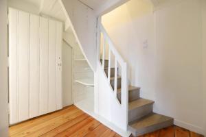 Una escalera en una casa con paredes blancas y suelos de madera. en La maison verte, en Annecy