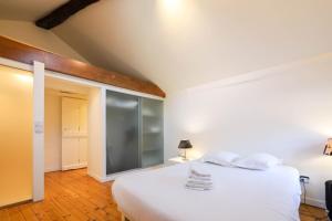 1 dormitorio con 1 cama blanca y pared de cristal en La maison verte, en Annecy
