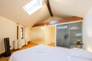 Un dormitorio con una cama blanca y una ventana. en La maison verte, en Annecy