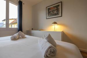 ein Schlafzimmer mit einem weißen Bett und Handtüchern darauf in der Unterkunft Le Boudoir bleu - 2 chambres in Annecy