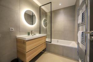 La salle de bains est pourvue d'un lavabo, d'une baignoire et d'un miroir. dans l'établissement Le Superbe - T4 avec parking à 5 min du lac - 4, à Annecy