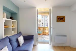 een woonkamer met een blauwe bank en een open deur bij Le Royale w balcony in Annecy