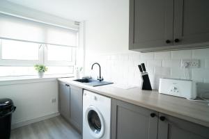 a kitchen with a washing machine and a sink at Deedes Apartment in Airdrie