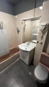 a bathroom with a sink and a toilet and a tub at Hôtel Marie Louise in Enghien-les-Bains