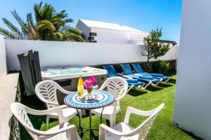 een patio met stoelen, een tafel en een hot tub bij Villa Alegranza - LH190 By Villas Now Ltd in Playa Blanca