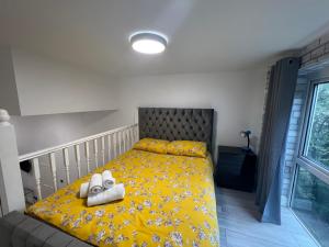 a bedroom with a yellow bed with towels on it at Comfy Apartments - Finchley Road in London