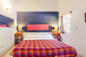 a bedroom with a large bed with a colorful blanket at Framadani Villas Gold Standard Certified in San Ignacio