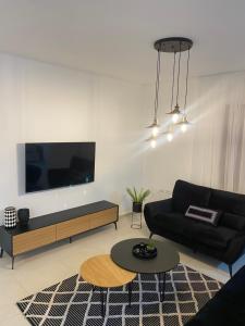 a living room with a black couch and a tv at מצפור הכנרת- דירת גן לאירוח in Tiberias