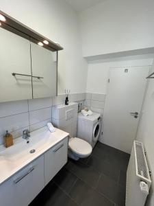 uma casa de banho com um WC, um lavatório e um espelho. em Premium Apartment 70qm 2 Zimmer Küche, Balkon, Smart TV, WiFi em Aalen