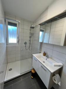 y baño blanco con lavabo y ducha. en Premium Apartment 70qm 2 Zimmer Küche, Balkon, Smart TV, WiFi en Aalen