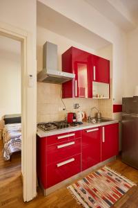 La cuisine est équipée de placards rouges et d'un four avec plaques de cuisson. dans l'établissement Silent and Cosy apartment, à Bologne