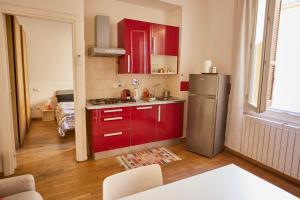 La cuisine est équipée de placards rouges et d'un réfrigérateur en acier inoxydable. dans l'établissement Silent and Cosy apartment, à Bologne
