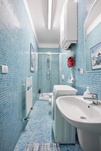 La salle de bains est pourvue de carrelage bleu, d'un lavabo et de toilettes. dans l'établissement Silent and Cosy apartment, à Bologne