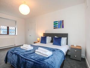 Un dormitorio con una cama azul y blanca con toallas. en Spacious 6 Sleeper - Great Location - Legoland - Parking, en Windsor