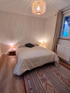 Un dormitorio con una gran cama blanca y una lámpara de araña. en Appartement dans un corps de ferme alsacien en Mittelhausbergen