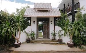 a house with potted plants in front of a door at The Courtyard Chiangrai in Chiang Rai