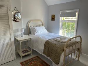 a white bedroom with a bed and a window at Charming country cottage in quiet rural setting 