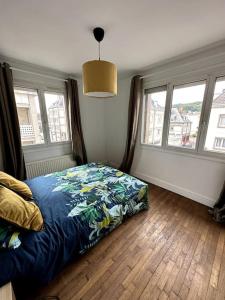 1 Schlafzimmer mit einem Bett mit blauer Decke und 2 Fenstern in der Unterkunft François Mitterrand 2 in Elbeuf