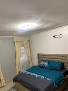 a bedroom with a bed with blue sheets and a window at Lovely 3 bedroom duplex in Ikeja GRA in Ikeja
