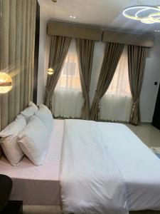 a large white bed in a room with windows at Lovely 3 bedroom duplex in Ikeja GRA in Ikeja