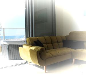 a couch in a living room with a large window at Beach Suite Israel- Private Jacuzzi Sea View Balcony, Off-Site Spa ביץ סוייט ישראל- ג'קוזי פרטי עם נוף ים, אפשרות לספא מוזל in Ashqelon