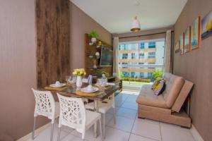 a dining room with a table and chairs and a couch at Flat em Porto de Galinhas - Muro Alto Clube in Porto De Galinhas