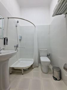 a white bathroom with a toilet and a sink at Hostel DANEXAN APA in Nukus