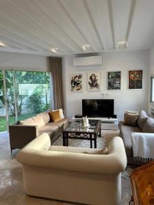 a living room with couches and a tv and a table at Villa Carthage - Proche Mer in Dar Salah Bey