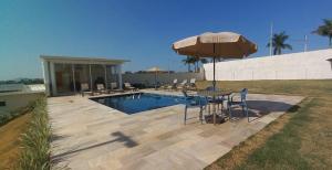 um pátio com uma mesa e um guarda-sol ao lado de uma piscina em Pousada Vila Craton Canastra em São João Batista do Glória