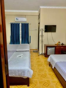 um quarto de hotel com duas camas e uma televisão de ecrã plano em Khánh Vân - VT Cloud mini Hotel em Vung Tau