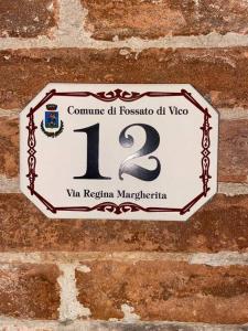 a sign on a brick wall with the number at La casetta di fossato in Fossato di Vico