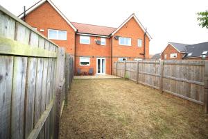 uma cerca em frente a uma casa de tijolos em Ashington - 2 Bedroom House - Beautifully Decorated & Furnished - Large Garden em Ashington