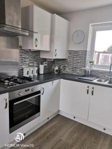 a kitchen with white cabinets and a stove top oven at Olive and Carols Walsall Stays in Walsall