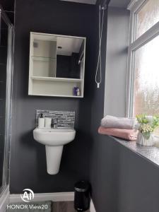 a bathroom with a white sink and a mirror at Olive and Carols Walsall Stays in Walsall