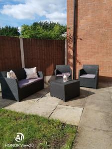 three wicker chairs and a table on a patio at Olive and Carols Walsall Stays in Walsall