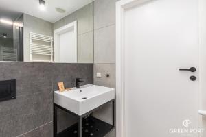 a bathroom with a white sink and a mirror at GreenPort Apartamenty Kołobrzeg - Dining & SPA in Kołobrzeg