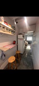 a small kitchen with a refrigerator and two stools at Studio Fabriketa in Novo Hamburgo