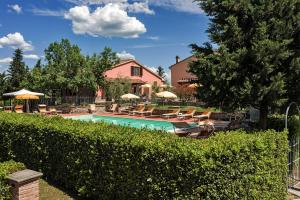 a swimming pool with chairs and umbrellas next to a house at La Casanuova in Lajatico