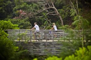 two people walking across a bridge in a forest at Six Senses Con Dao - Turtle Island Paradise in Con Dao