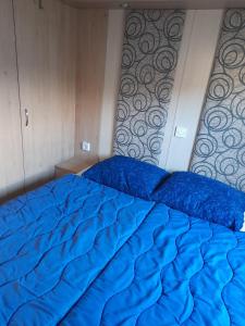 a bed with blue sheets in a bedroom at ZP 237 - Camping de Zandput in Vrouwenpolder