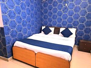 uma cama num quarto com uma parede azul em Atlas Inn Guest House em Nova Deli