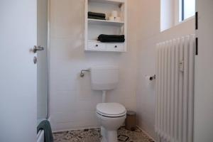 a white bathroom with a toilet and a cabinet at Gemütliches Apartment im Wald - Netflix & Prime in Marktleugast
