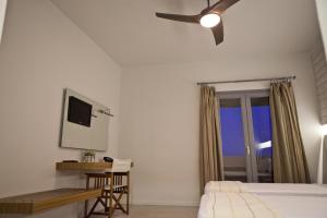 a bedroom with a bed and a desk and a ceiling fan at Xanthippi Hotel in Souvala