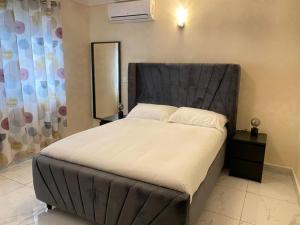 1 dormitorio con 1 cama grande y cabecero negro en After 5 Apartment 1- 3 spacious en-suite bedrooms en Freetown