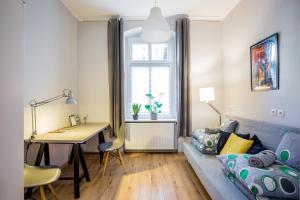salon z kanapą i biurkiem w obiekcie Wygodne pokoje w Gliwicach w mieście Gliwice