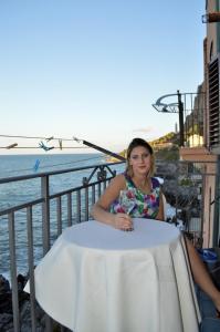 a woman sitting at a table next to the water at MiraMare Residence Cefalú in Cefalù