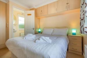 una camera da letto con un grande letto bianco con asciugamani sopra di 2 The Beeches - St Mabyn Cornwall a Saint Mabyn