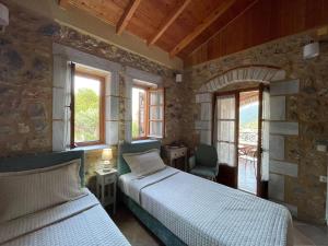two beds in a room with two windows at Panorama Stonehouse in Leonidio