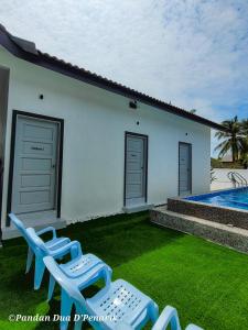 uma casa com duas espreguiçadeiras e uma piscina em Pandan Dua D'Penarik em Kampong Nyatoh