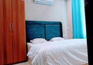 a bedroom with a large bed with a blue headboard at Staeg Hill View 2BHK - 602 in Indore
